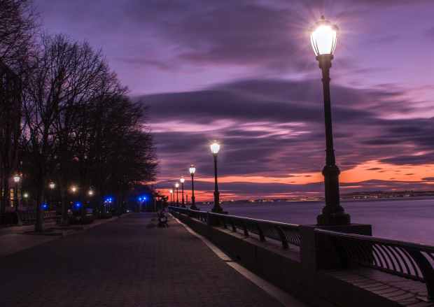 photography of turned on street lamps beside bay during night time